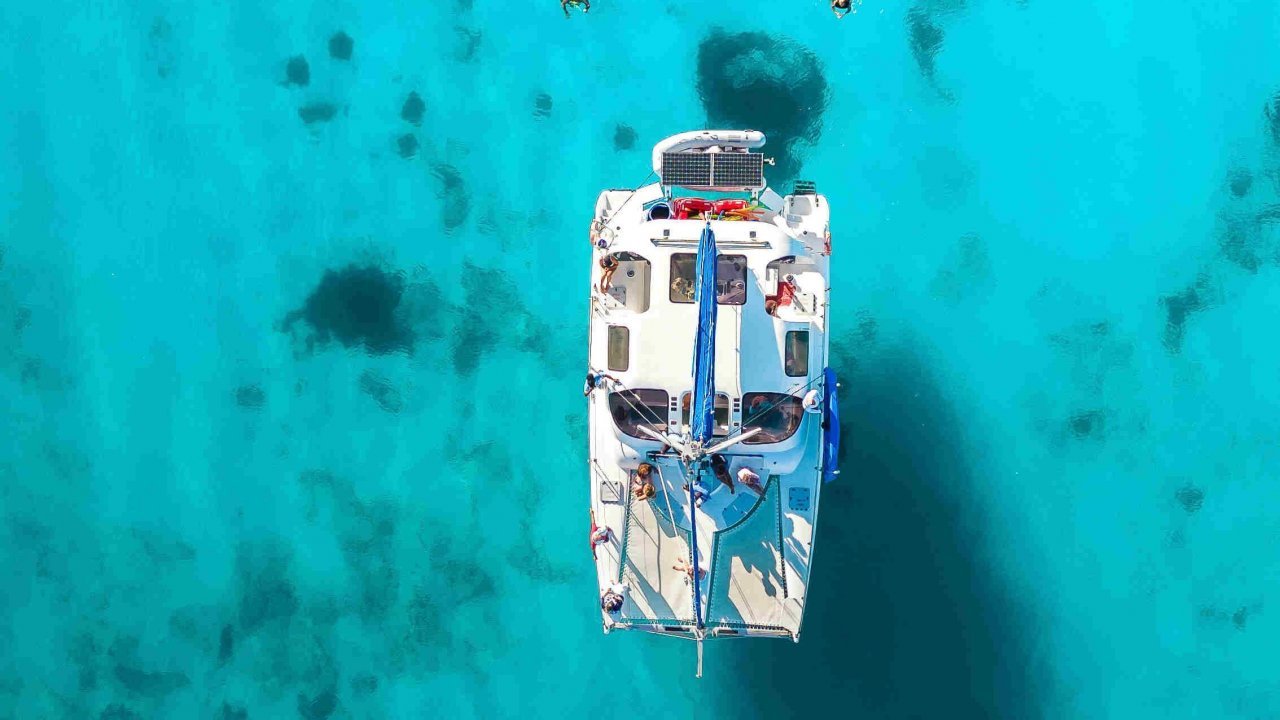 Aerial view of a catamaran sailing in the crystal-clear turquoise waters of St. Maarten.