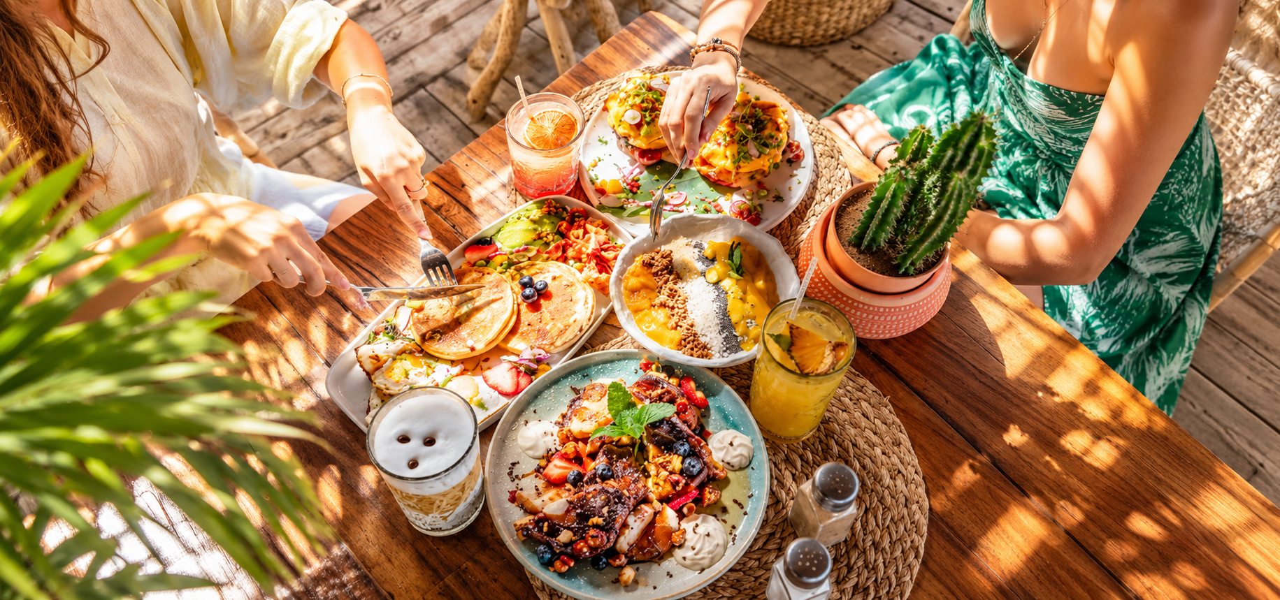 Colorful tropical breakfast and brunch spread with pancakes, fresh fruit and drinks at an outdoor dining table