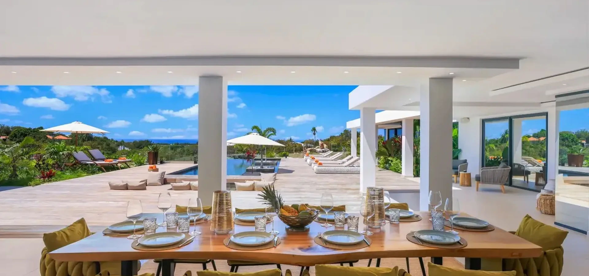 Elegant dining table at a Caribbean villa overlooking a swimming pool and tropical surroundings